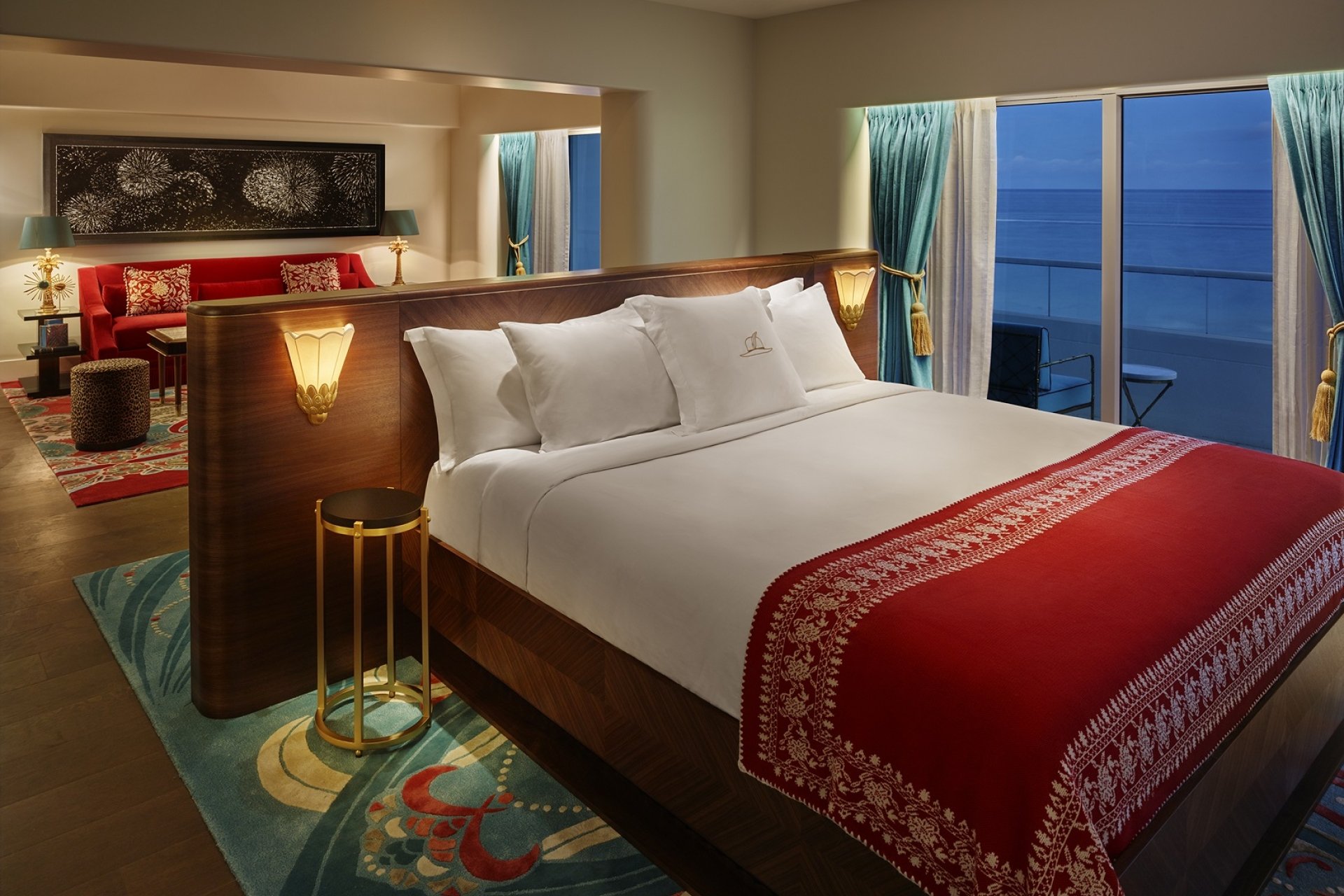 bed in hotel suite at night with windows to the ocean