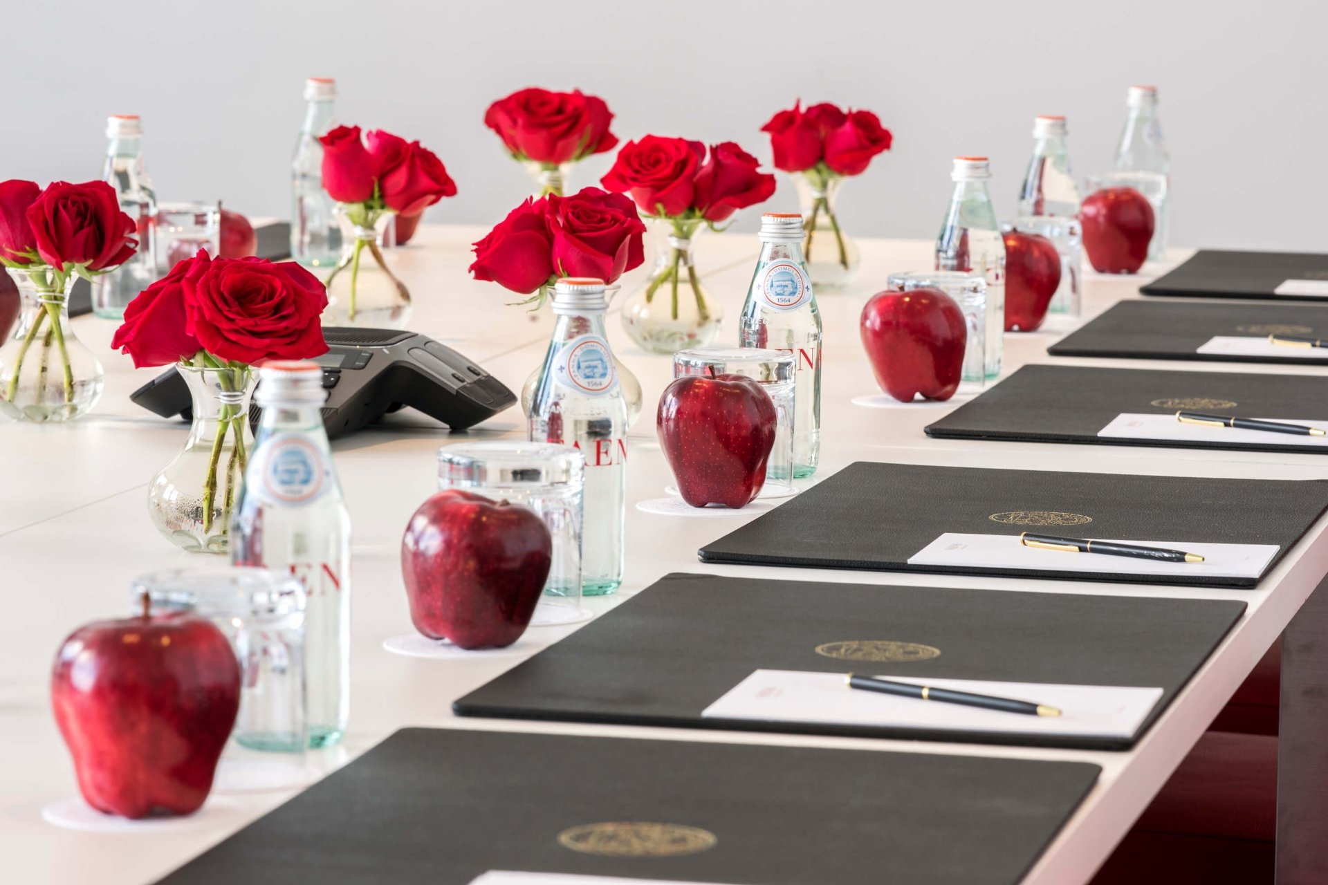 long table set up with padfolios, flowers and snacks