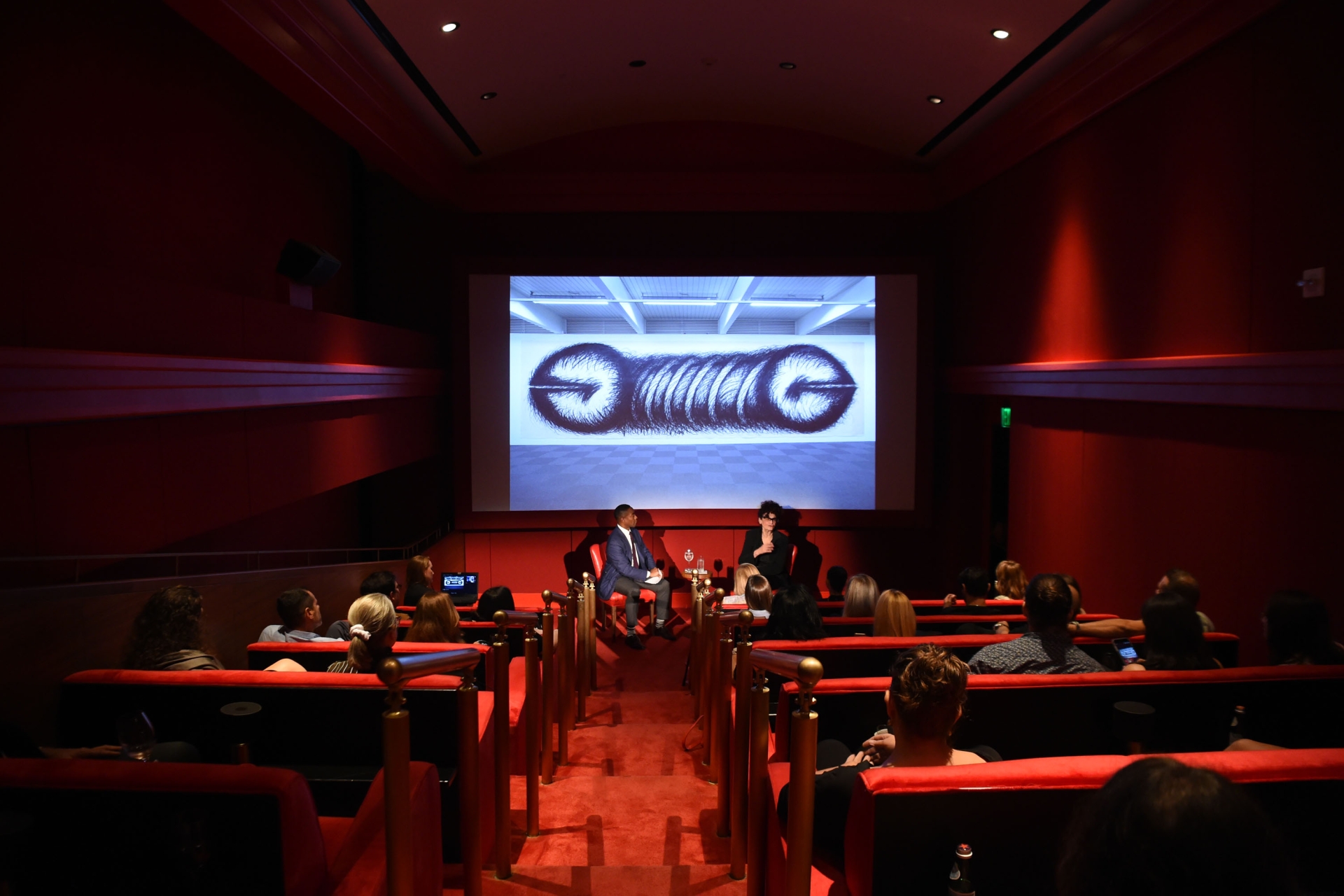interior shot of performance in screening room with people in seats and projection on screen