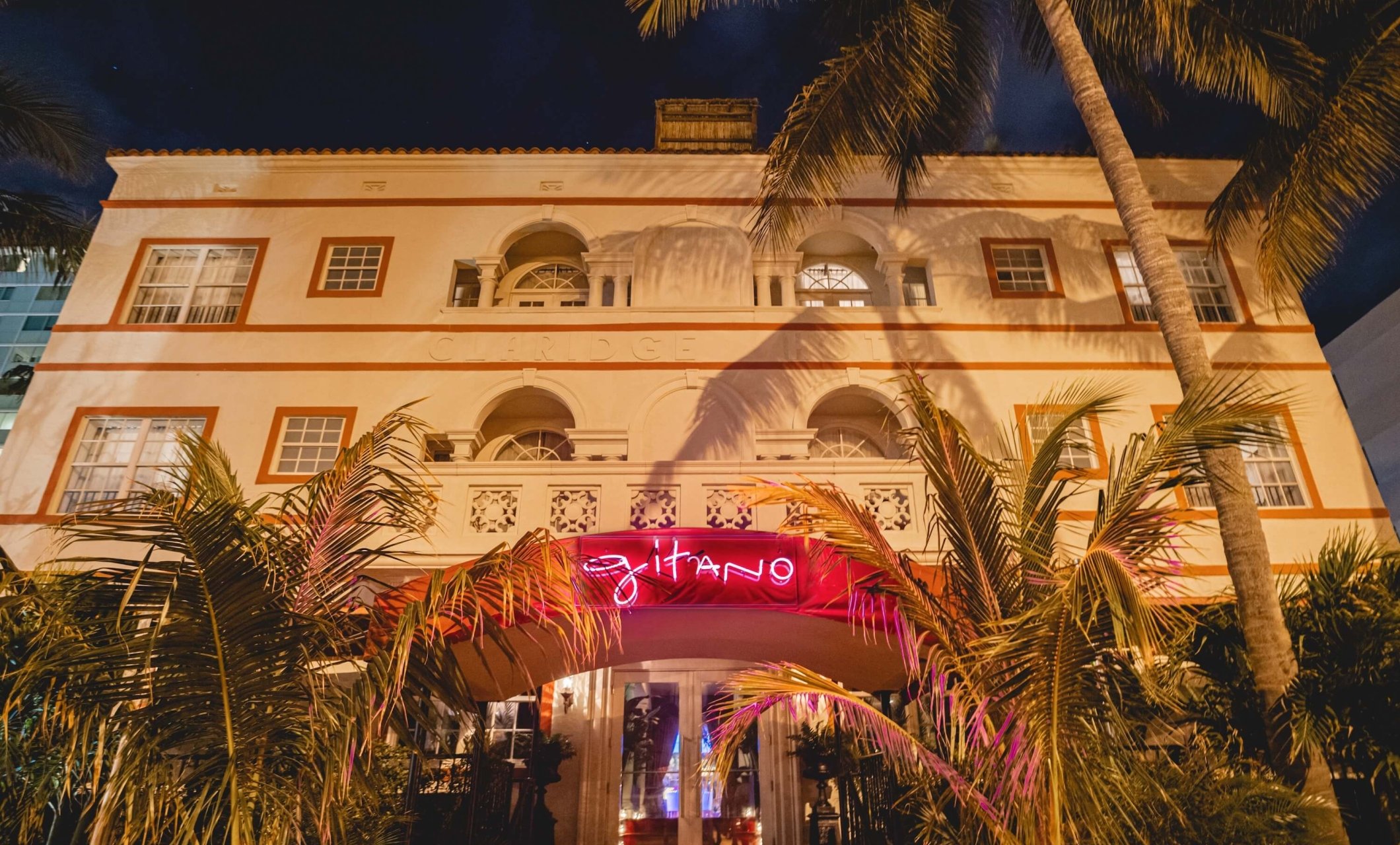 exterior front-side of Gitano MIami with lit-up pink neon sign