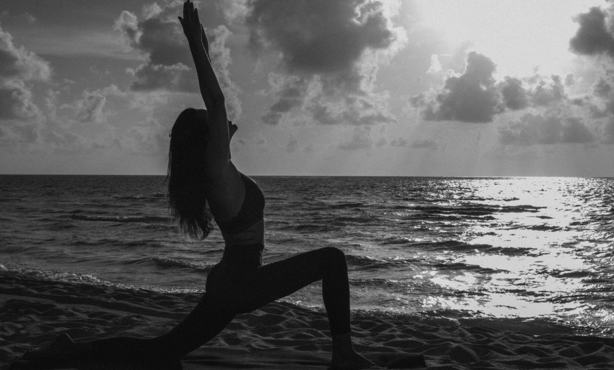 Woman doing yoga on the beach with a view of the ocean