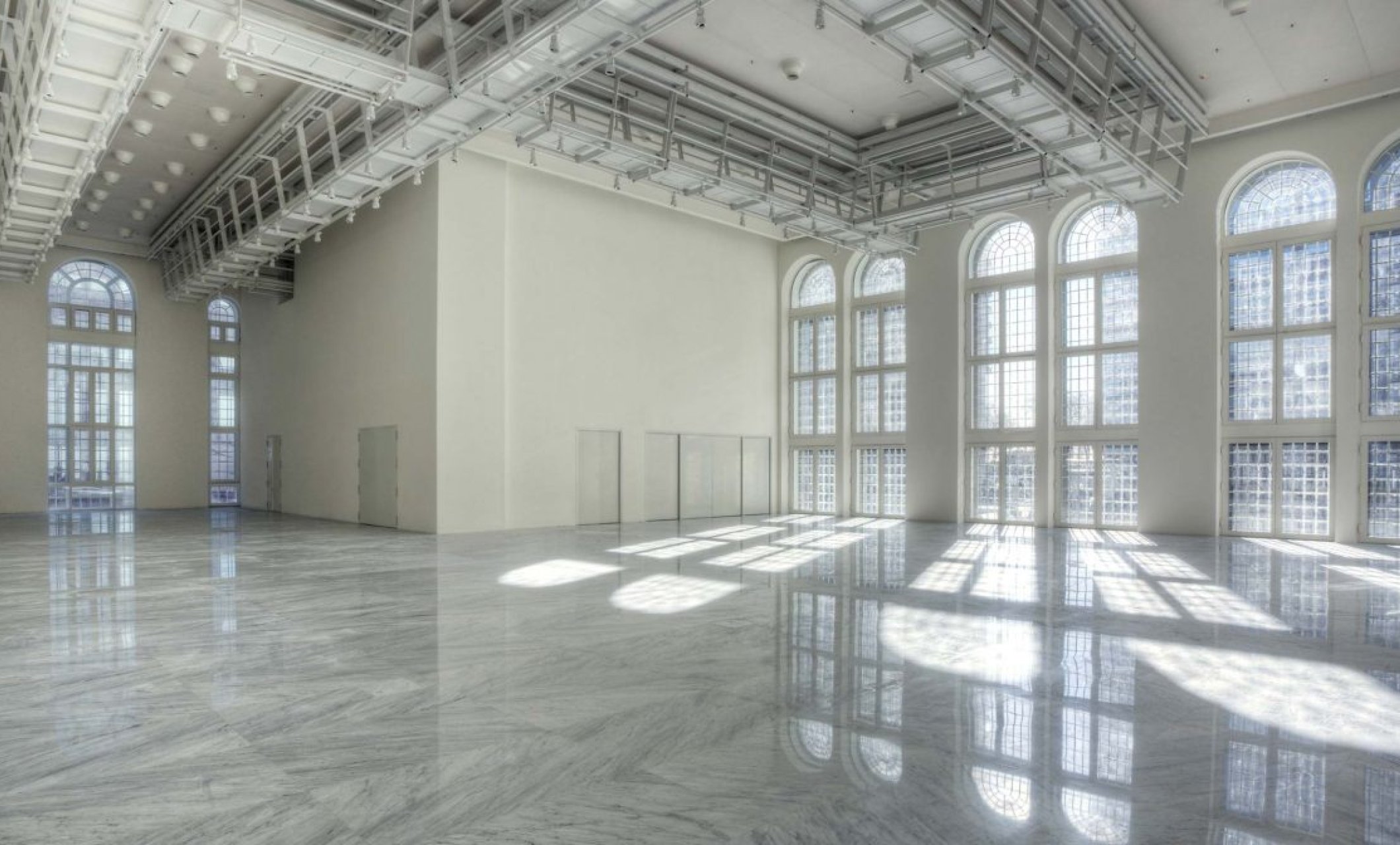 expansive white room with industrial ceiling and floor to ceiling windows
