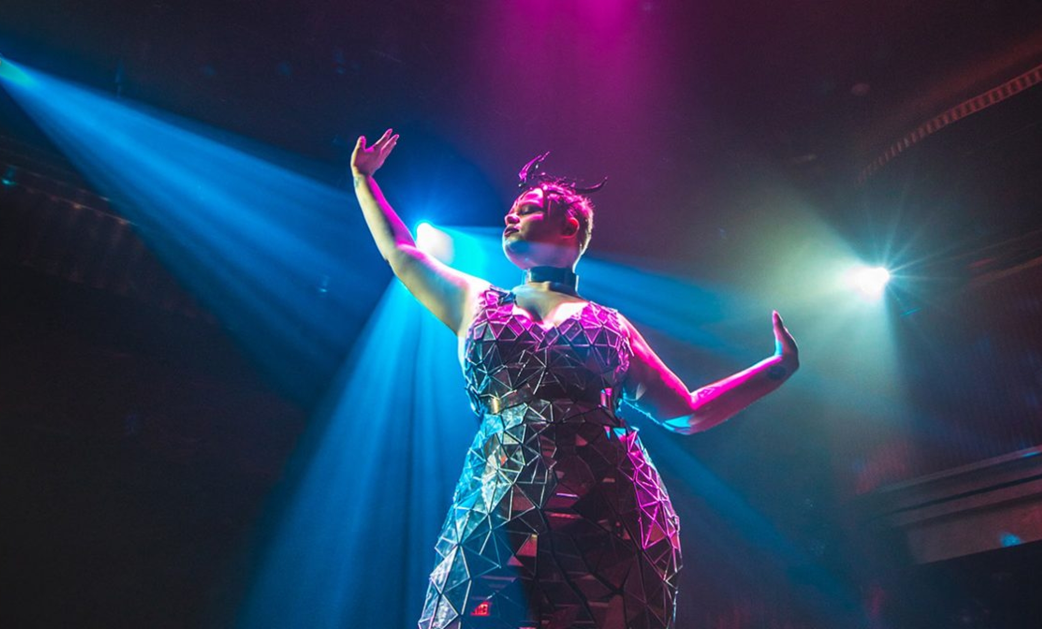 samsara performer in geometric dress holds arms out to their sides