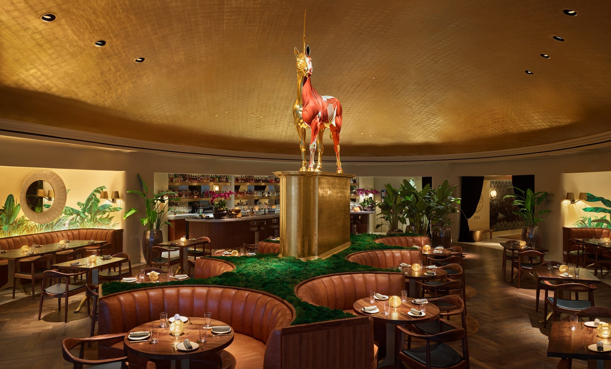 A stylish dining area with a statue of a deer, booths, and tables set for dinner.