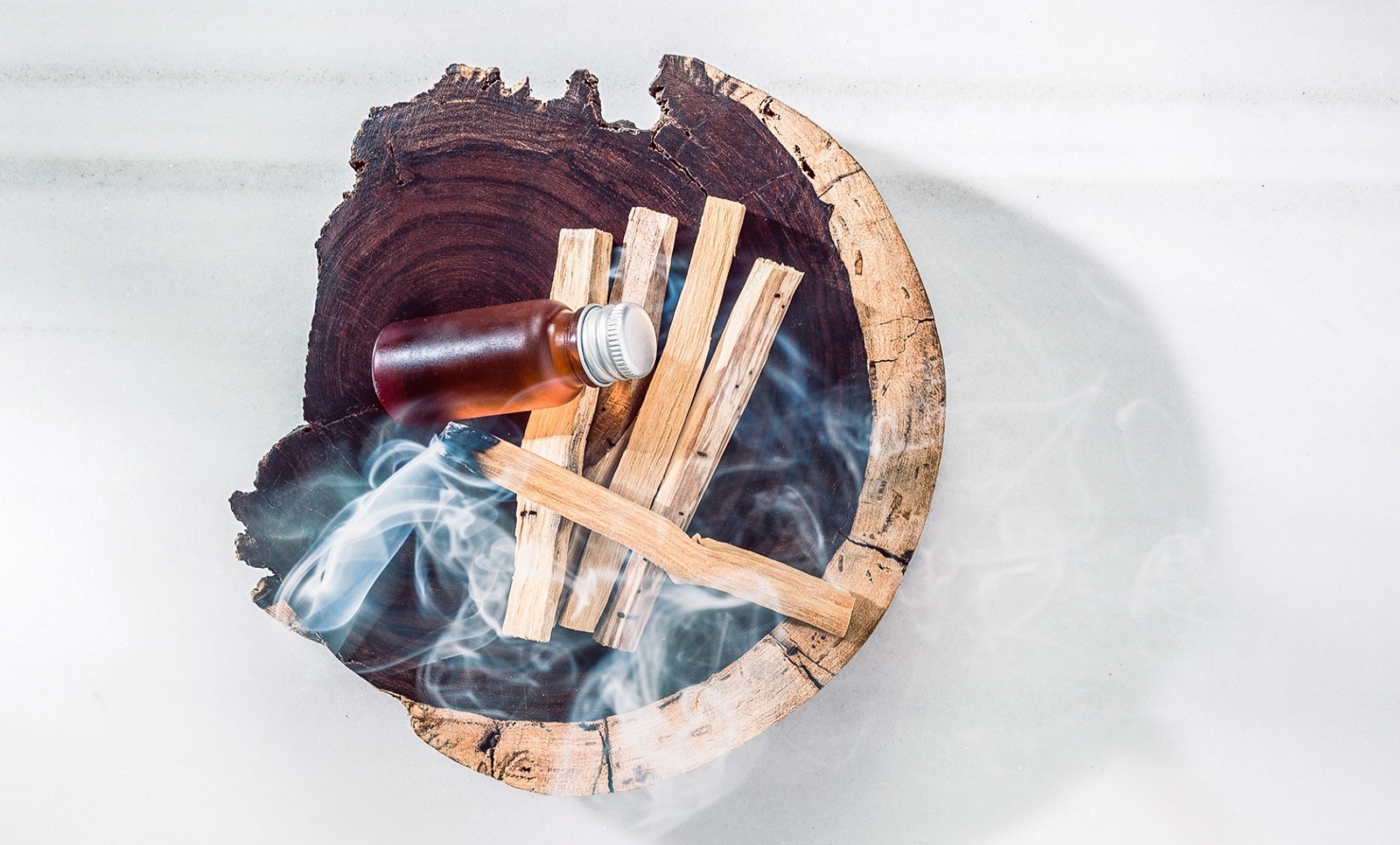wooden bowl with wood smoking and small bottle