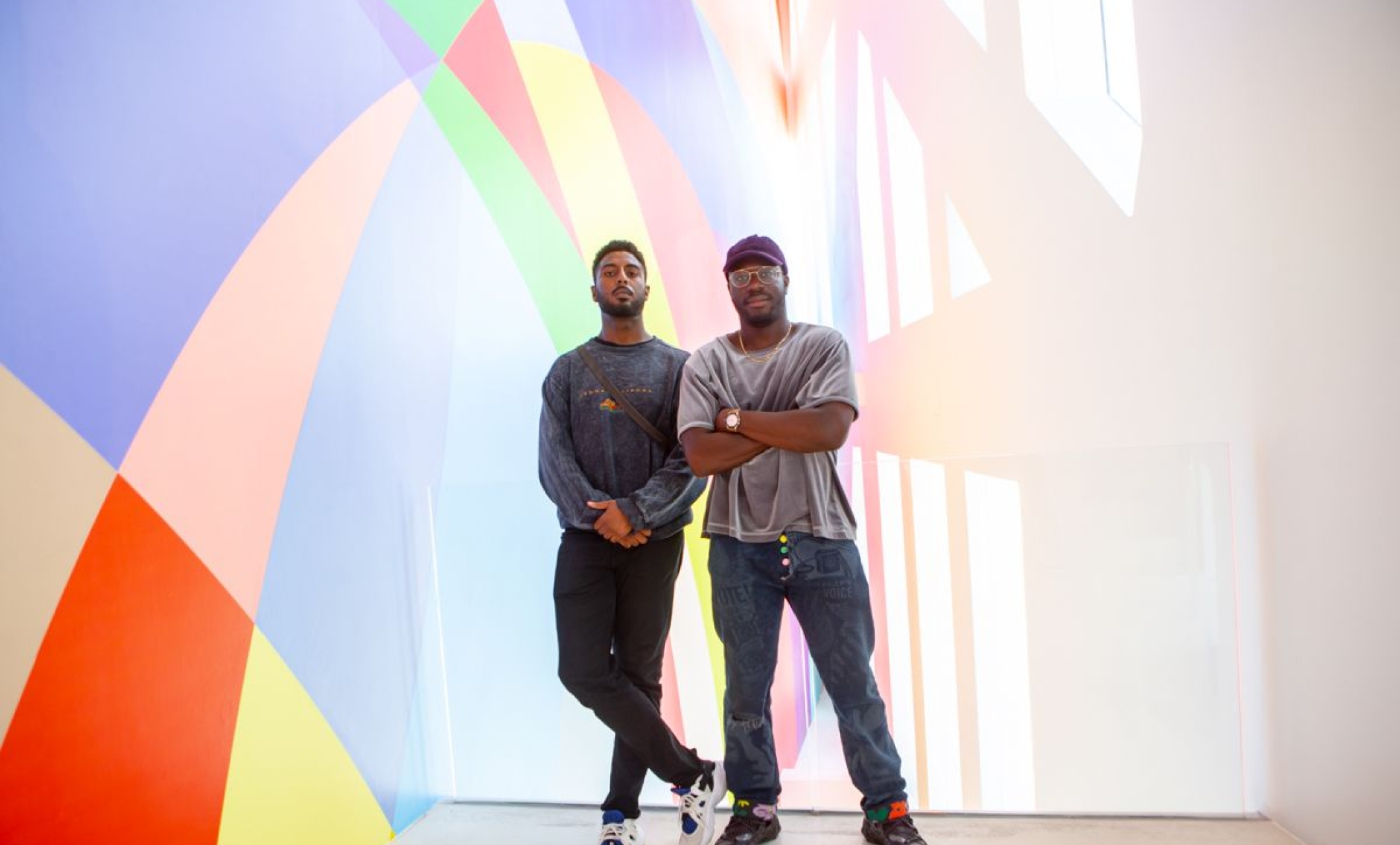 two men stand in front of colorful wall