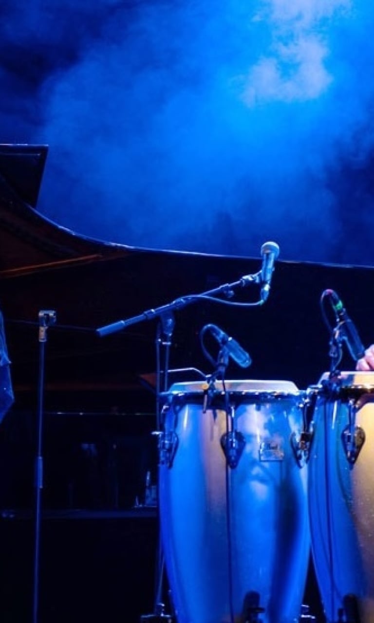 Congas and microphones on a blue-lit stage
