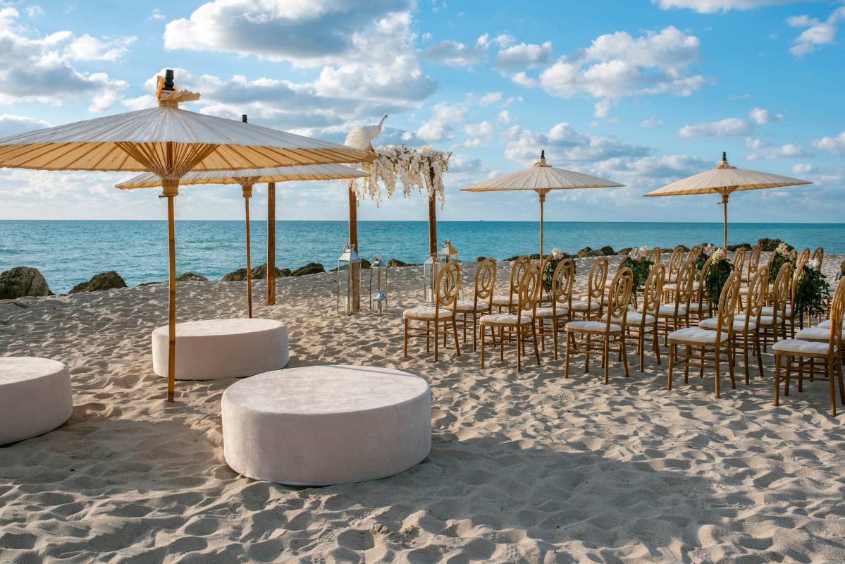chairs and umbrellas set up on the beach for a wedding ceremony