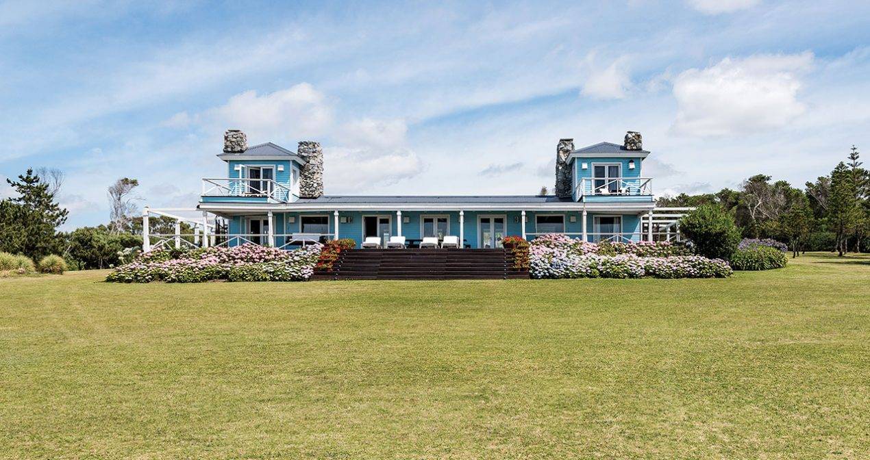 blue house sits on green lawn