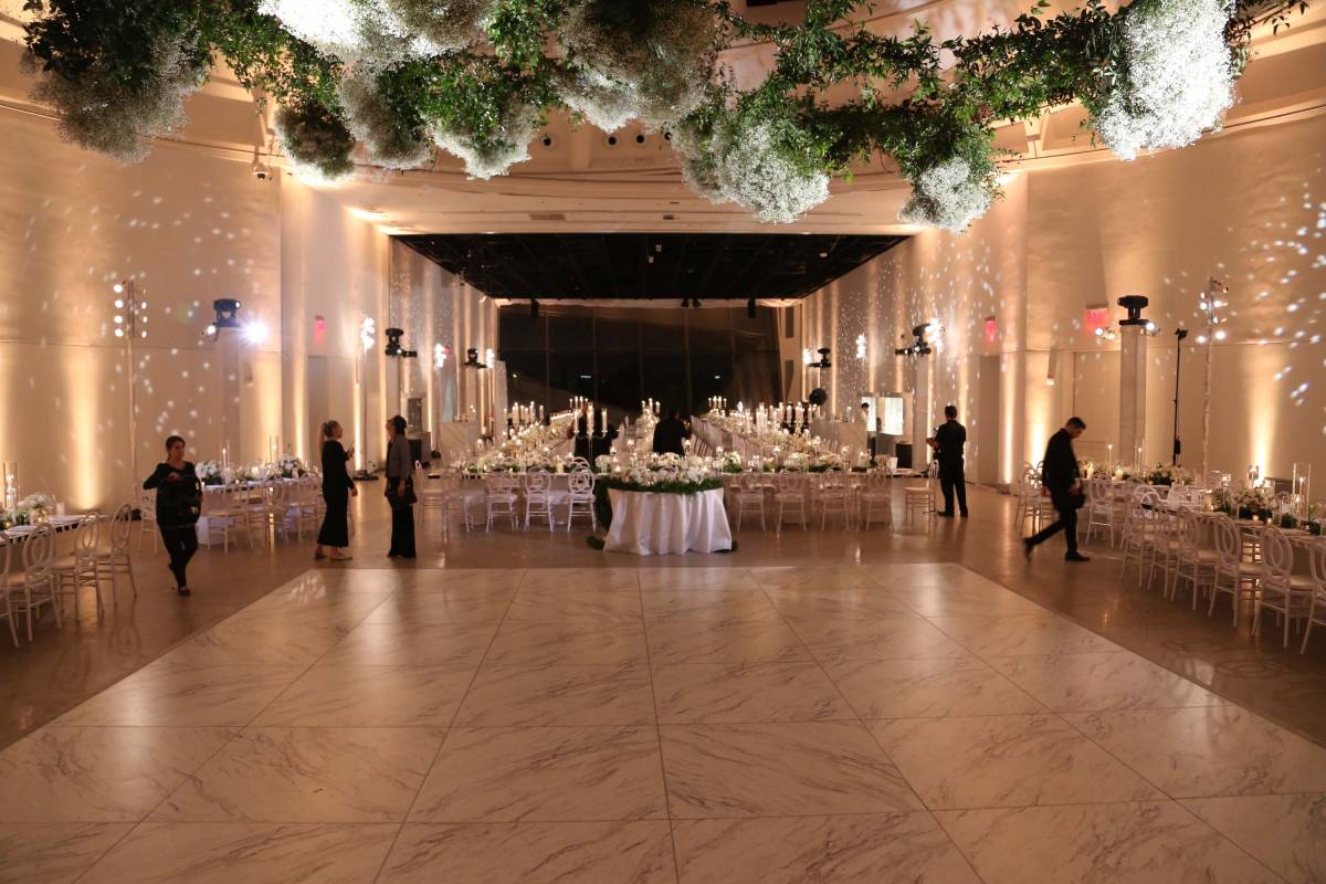 interior of wedding venue with floral and greenery on ceiling and staff mingling amongst stables
