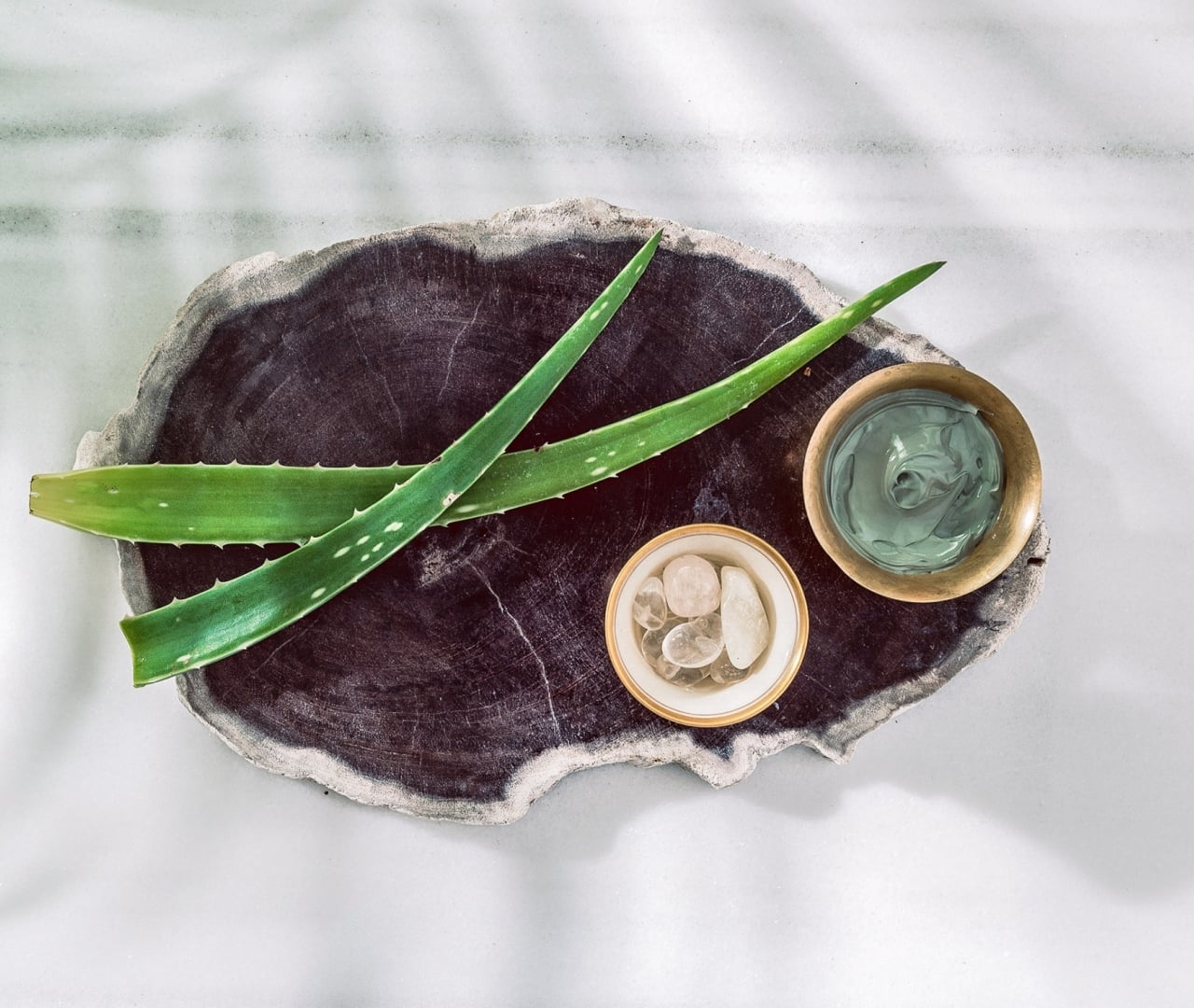 a wooden tray with aloe vera, stones, and cream