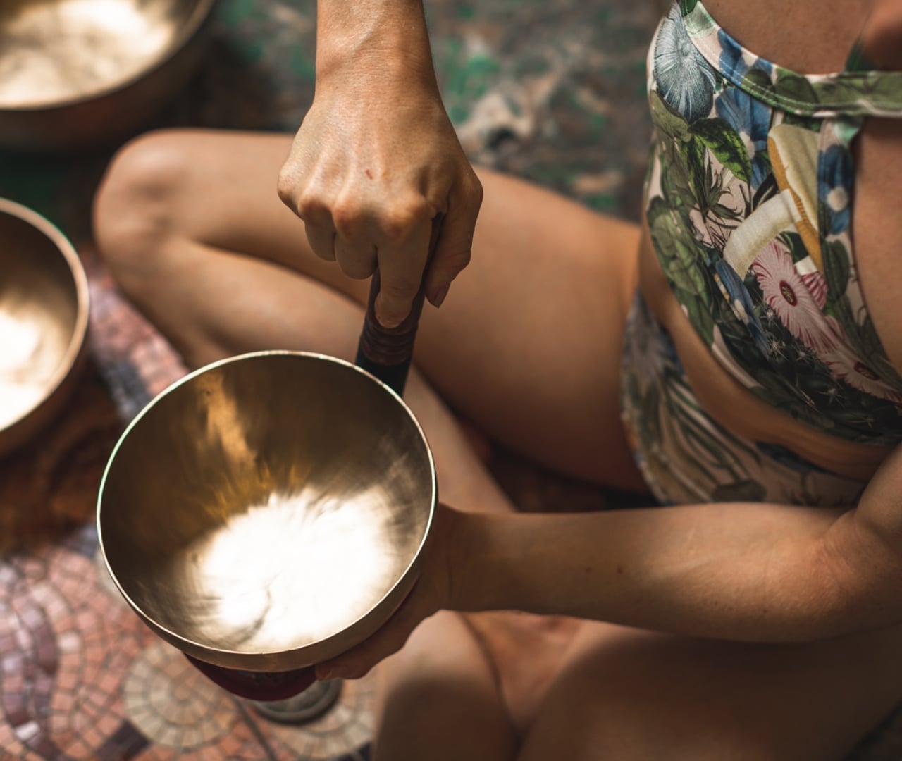 a woman in a bikini holding a tibetan singing bowl