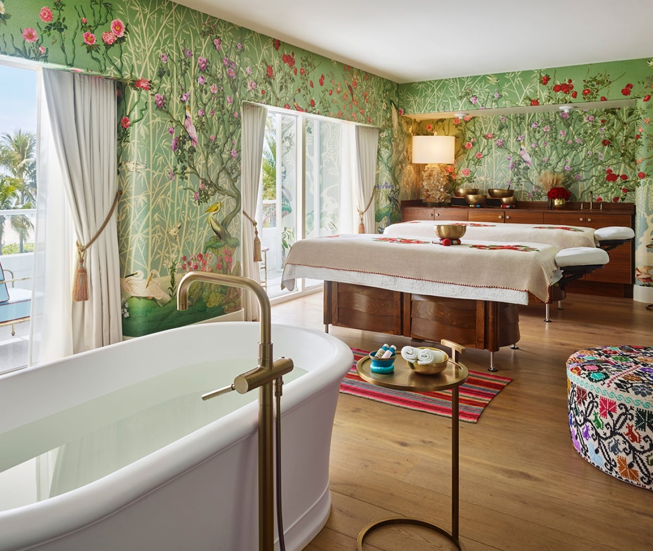 A serene spa room with a massage table, soaking tub, and tropical decor.