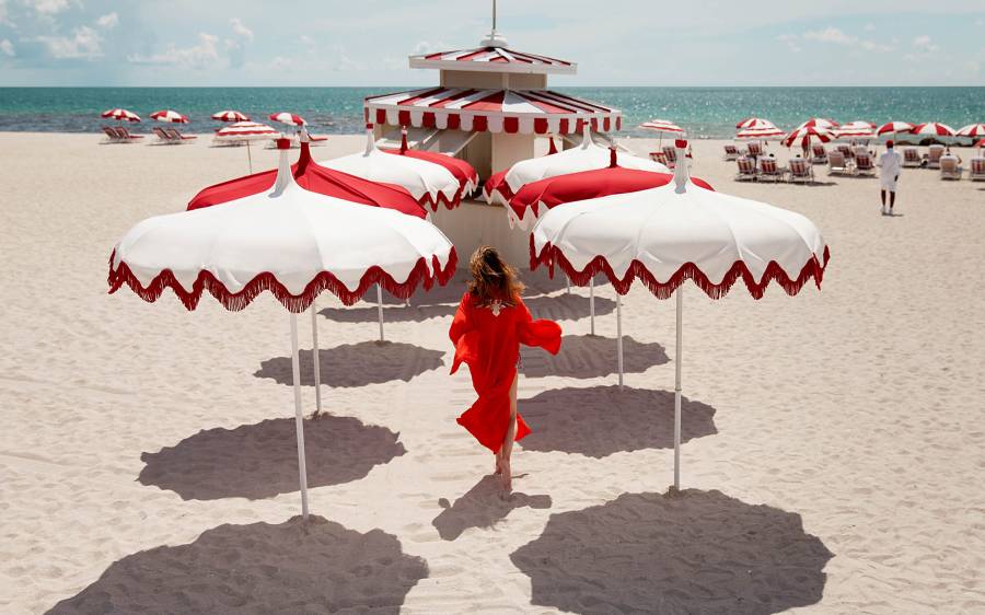 woman walking on the beach surrounded by white and red umbrellas