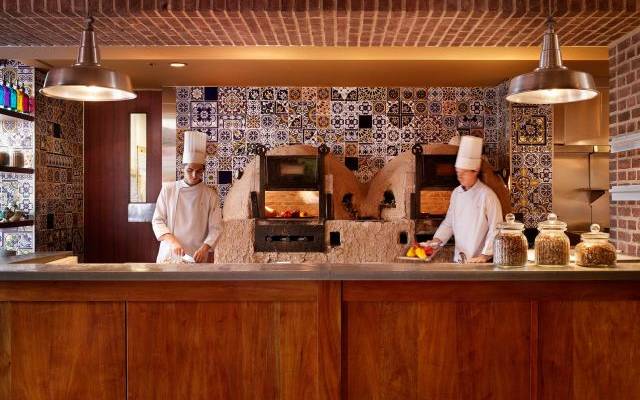 two chefs in kitchen in front of wood fired ovens