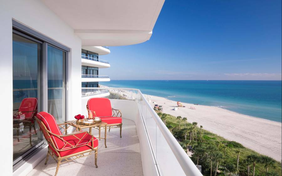 two red chairs sit on balcony overlooking ocean front beach