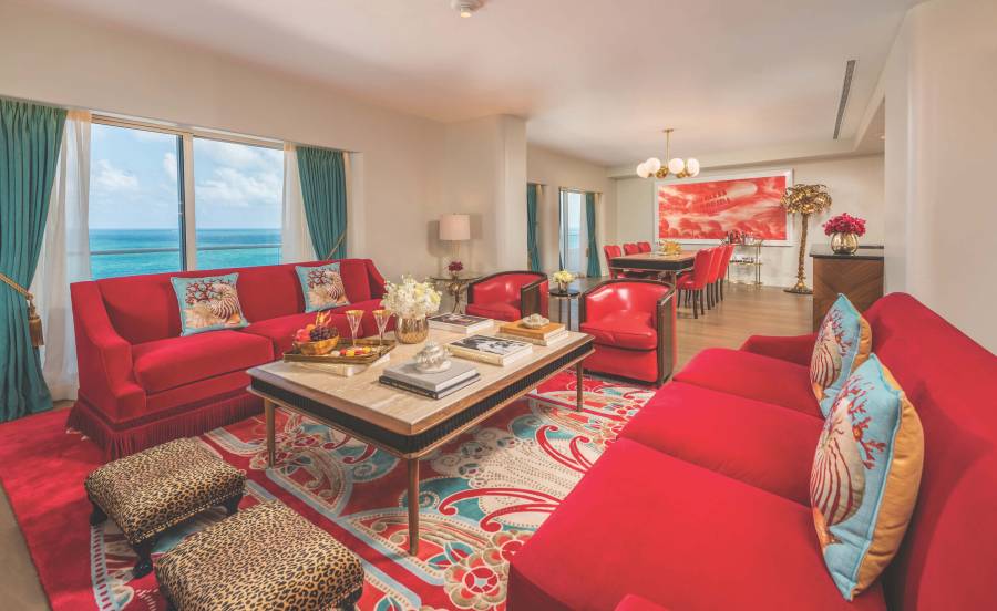 interior of sitting area with red couches, leopard print foot stools and the ocean visible through large window