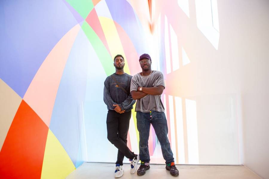 two men stand in front of colorful wall