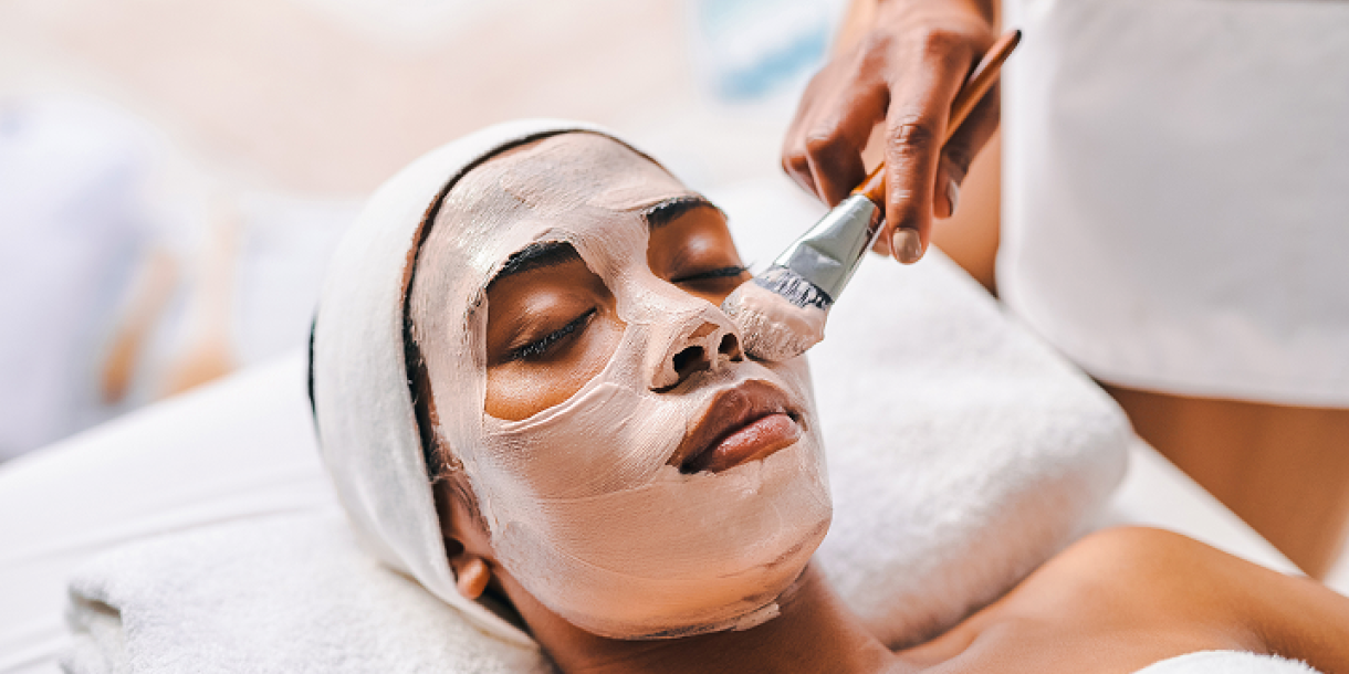 A woman receiving a facial treatment with a face mask being applied by a professional.
