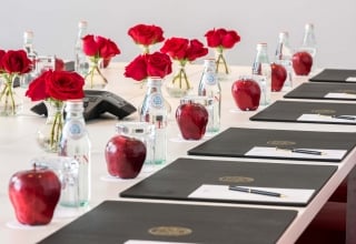 long table set up with padfolios, flowers and snacks