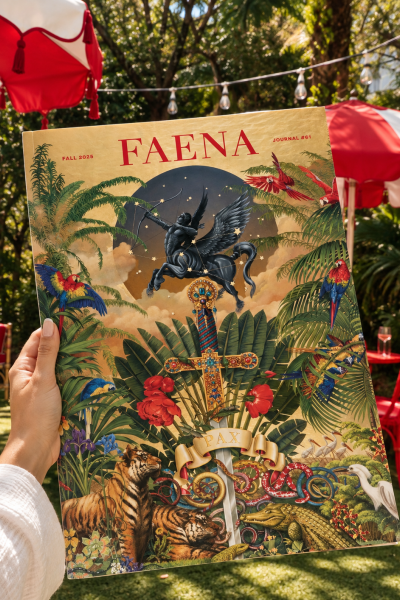 A hand holding Faena Journal’s illustrated cover against a lush tropical garden with signature red-and-white umbrellas.