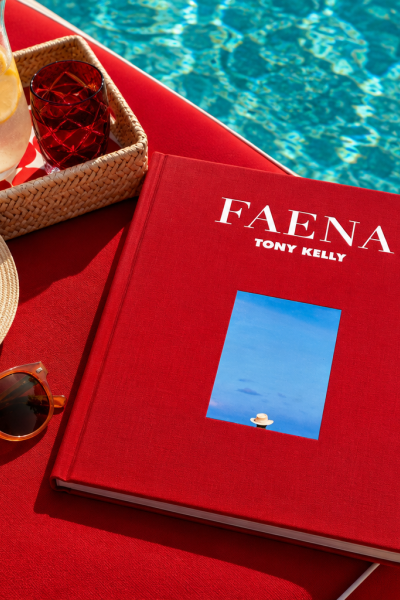 Red Faena coffee table book by the pool, styled with a straw hat, sunglasses, and a refreshing drink.