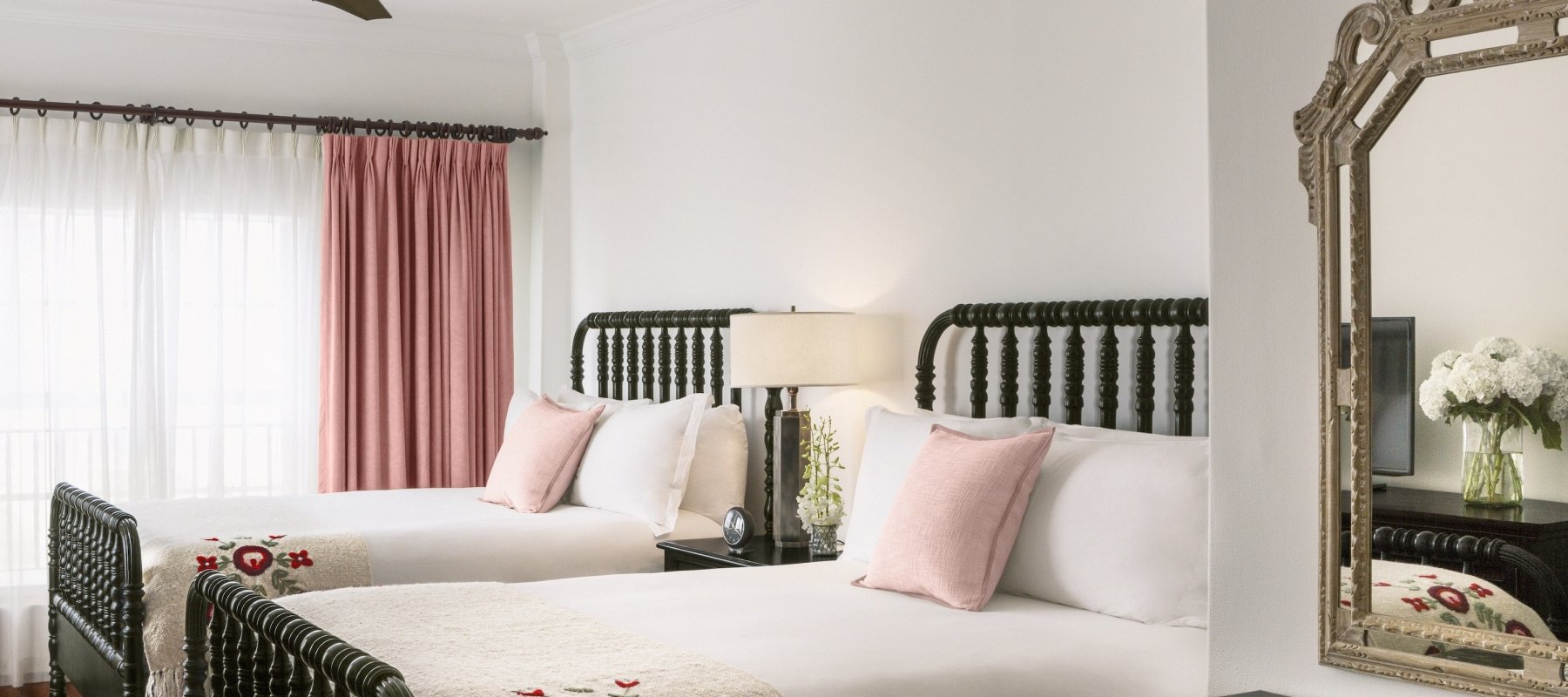 two beds with white sheets with mirror in foreground