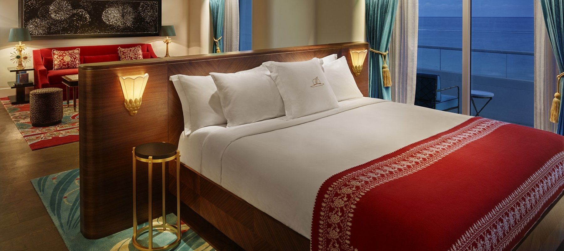 bed in hotel suite at night with windows to the ocean