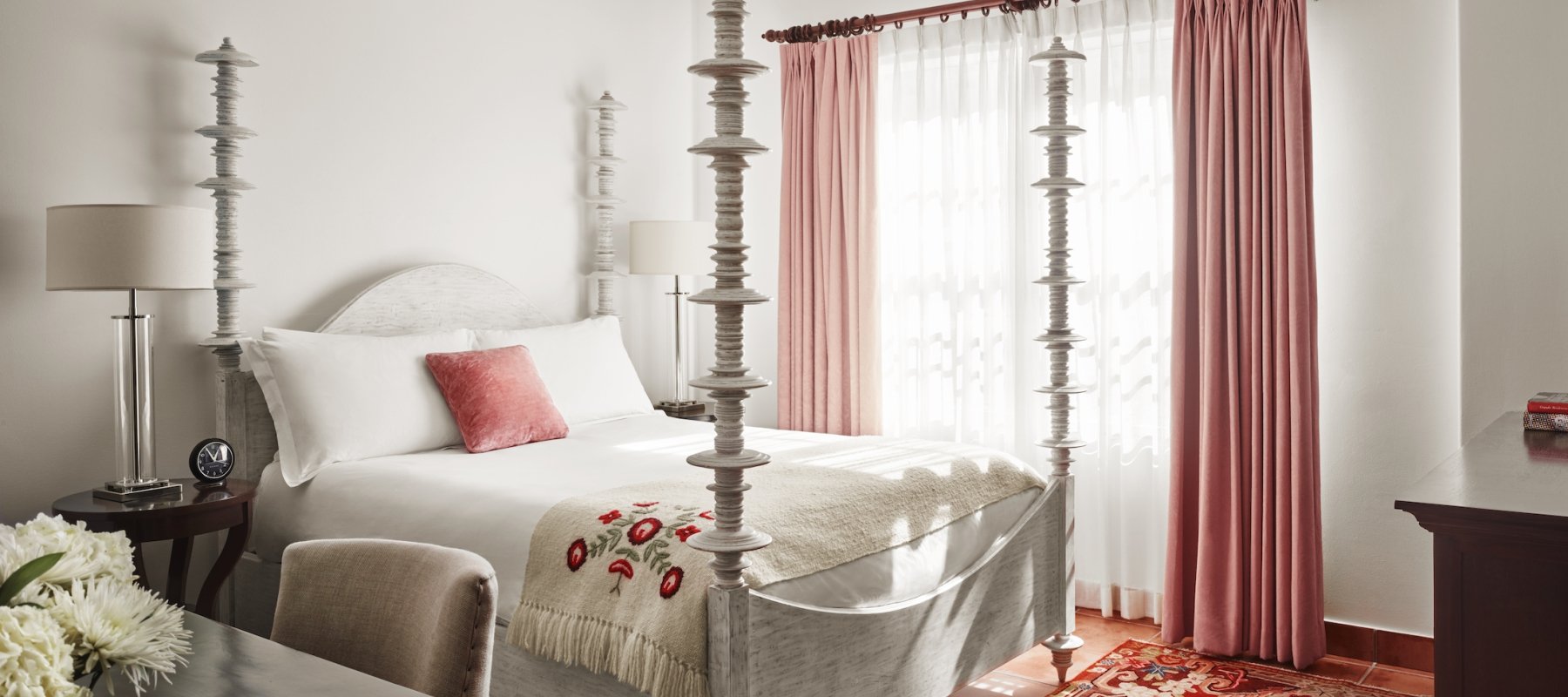 queen bed with four posts and pink curtained windows and red and gold carpet