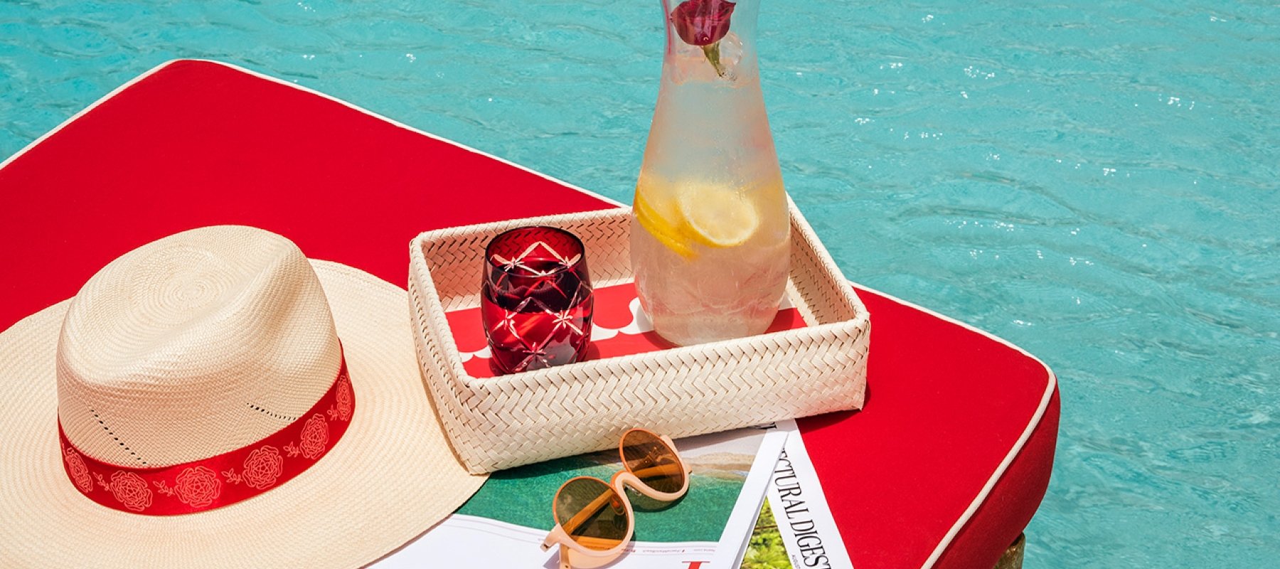 table next to pool with lemonade and a hat