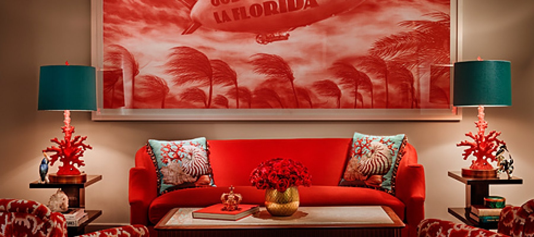 red couch sits between two teal lamps with a God Bless La Florida hung on the wall