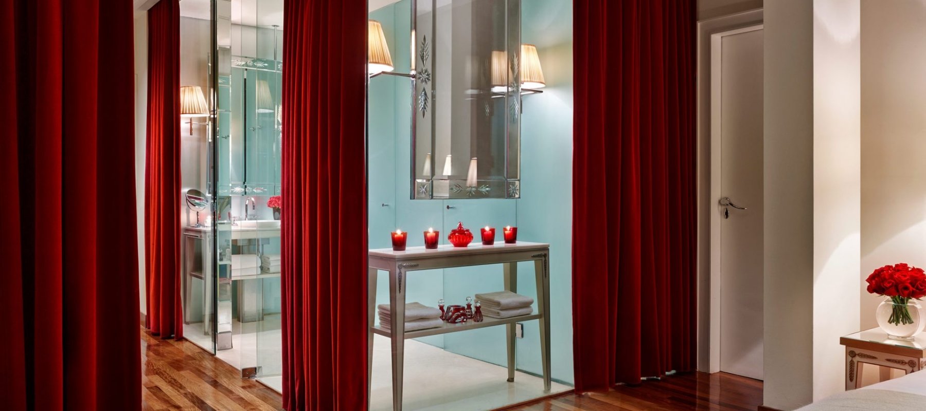 glass walled hotel suite bathroom with velvet curtains