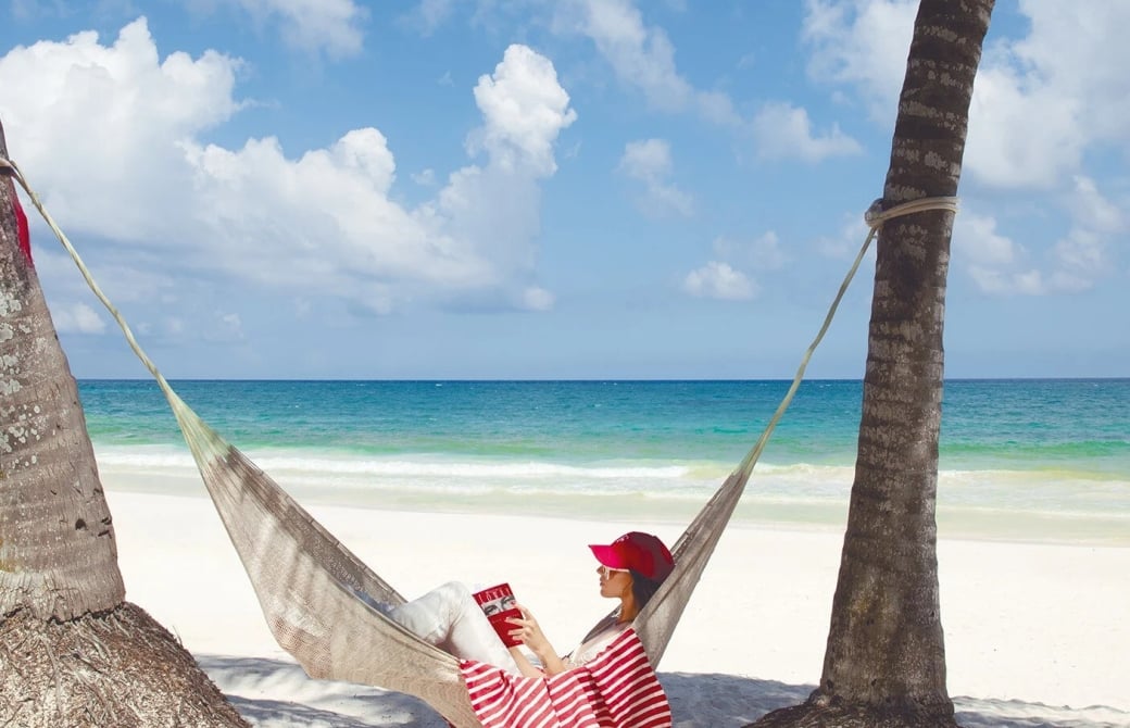 Woman in a hammock reading on the beach