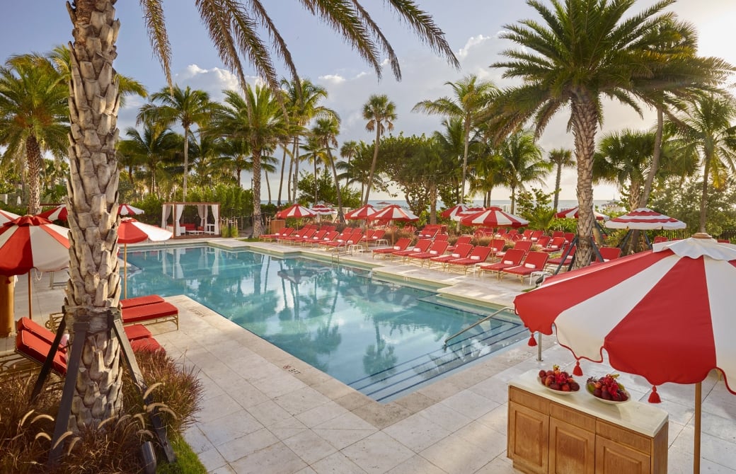 hotel pool surrounded by palm trees and umbrellas