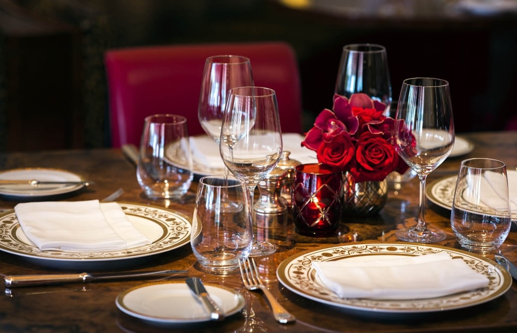 a formal dining table set with red roses and wine glasses