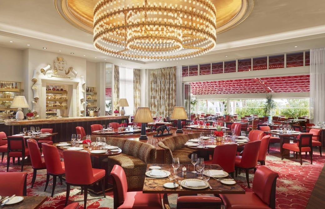 Seating area with colourful furniture and large chandelier overhead.