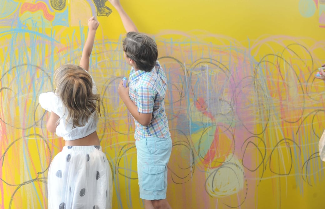 children drawing on a yellow wall
