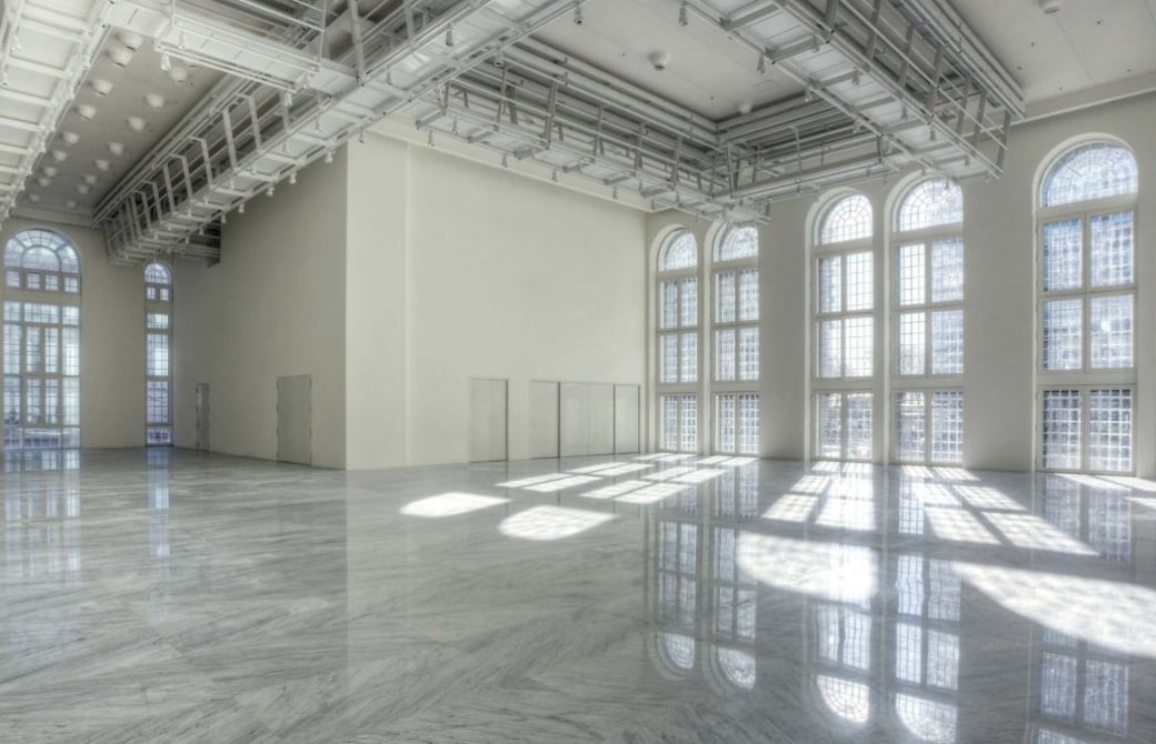 expansive white room with industrial ceiling and floor to ceiling windows