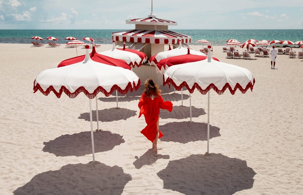 woman walking on the beach surrounded by white and red umbrellas