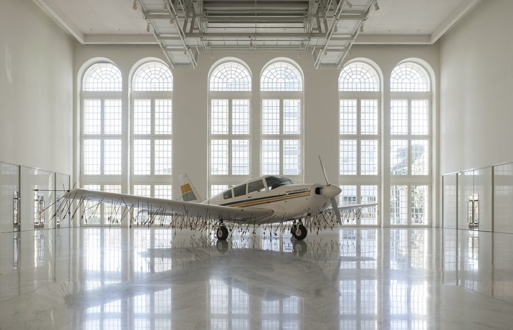Airplane with arrows piercing the wings in an art gallery
