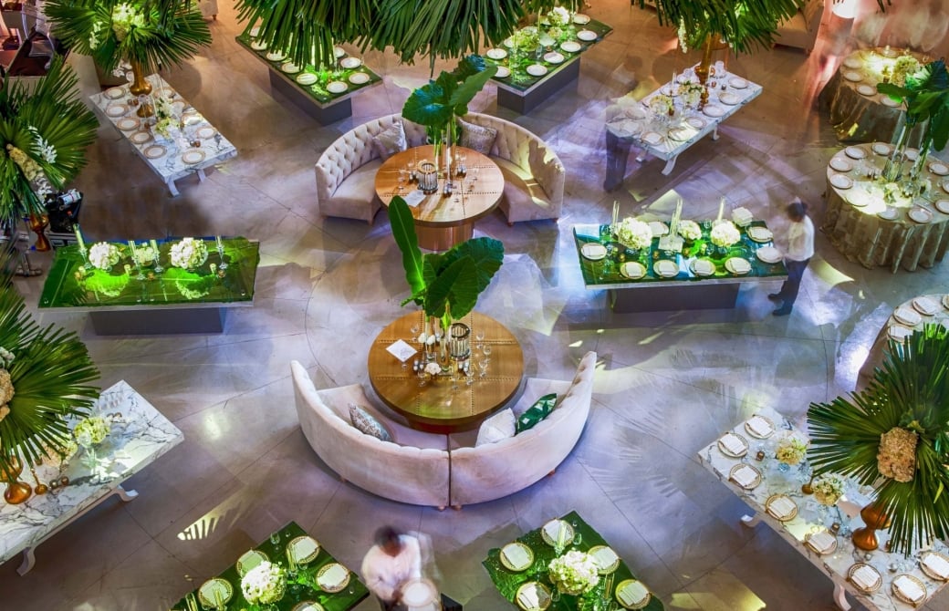 looking down on tables set up for dining with a lot of palm leaves as decoration