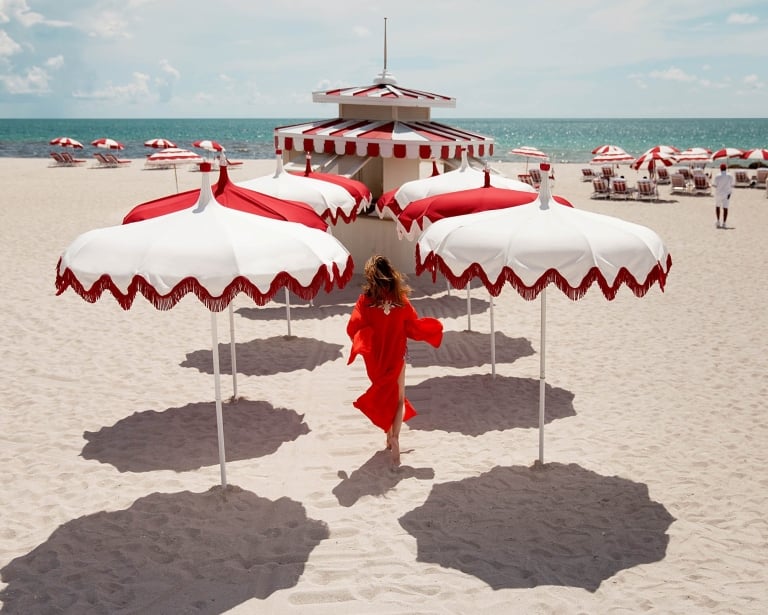 woman walking on the beach surrounded by white and red umbrellas