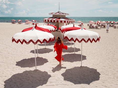 woman walking on the beach surrounded by white and red umbrellas