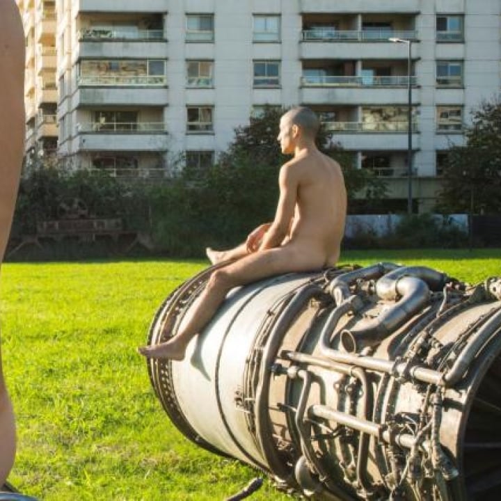 A nude man sitting on a sculpture