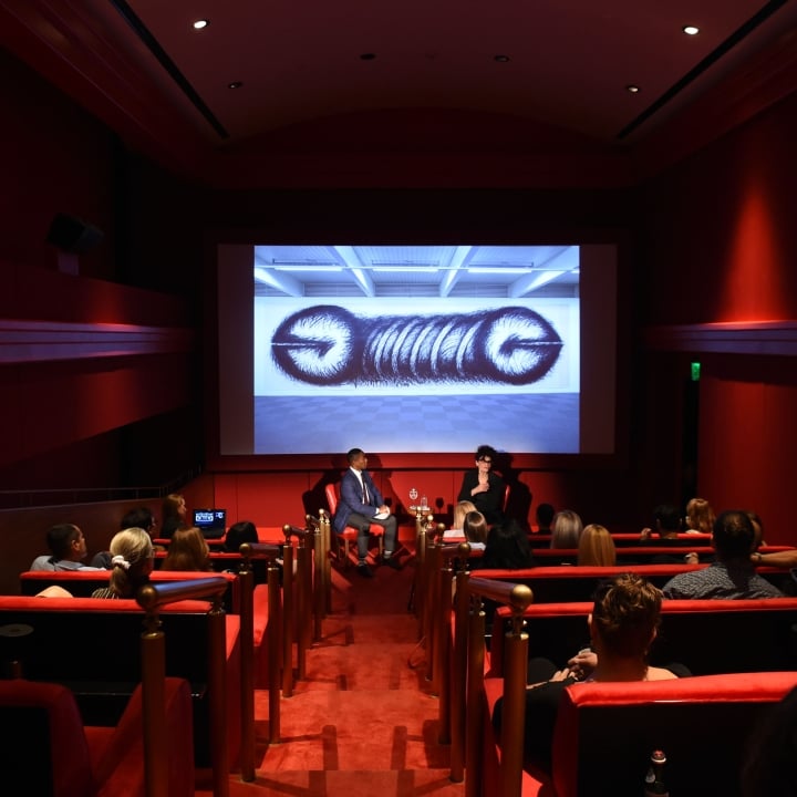 interior shot of performance in screening room with people in seats and projection on screen