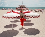 woman walking on the beach surrounded by white and red umbrellas