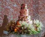 close up of wedding cake with floral arrangement at the base
