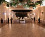 interior of wedding venue with floral and greenery on ceiling and staff mingling amongst stables 
