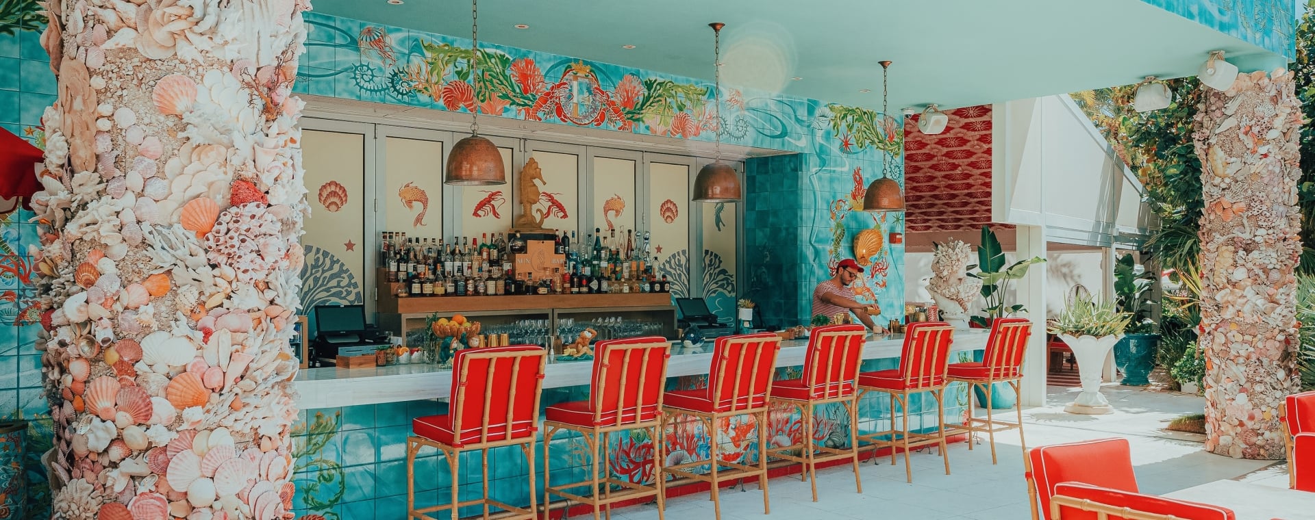 a bar with red chairs and a shell-covered counter