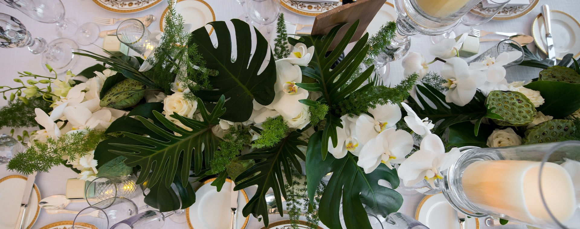 A formal dining table set with white tablecloth, flowers, candles, plates, and glasses.